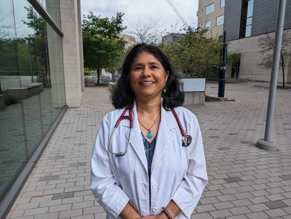 Dr. Tessy Kadavil, DNP, APRN, standing outside the clinic in her white coat